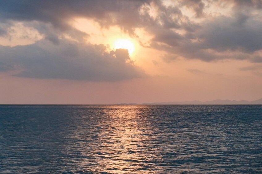 A sunset over a calm sea with clouds reflecting the sunlight. 3