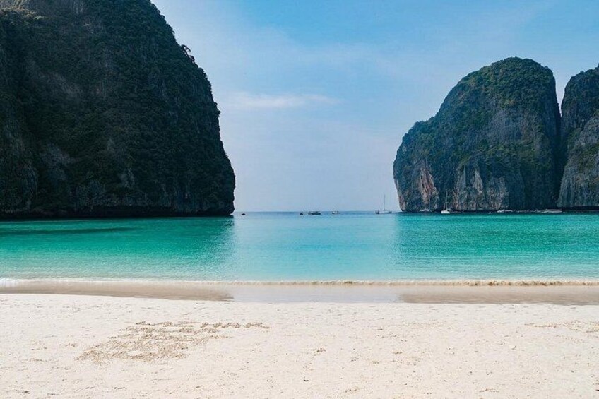 A beach with clear turquoise water, white sand, and large rock formations. 4