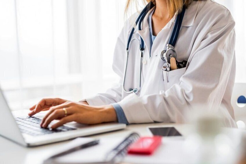 A person in a white coat using a laptop. 2