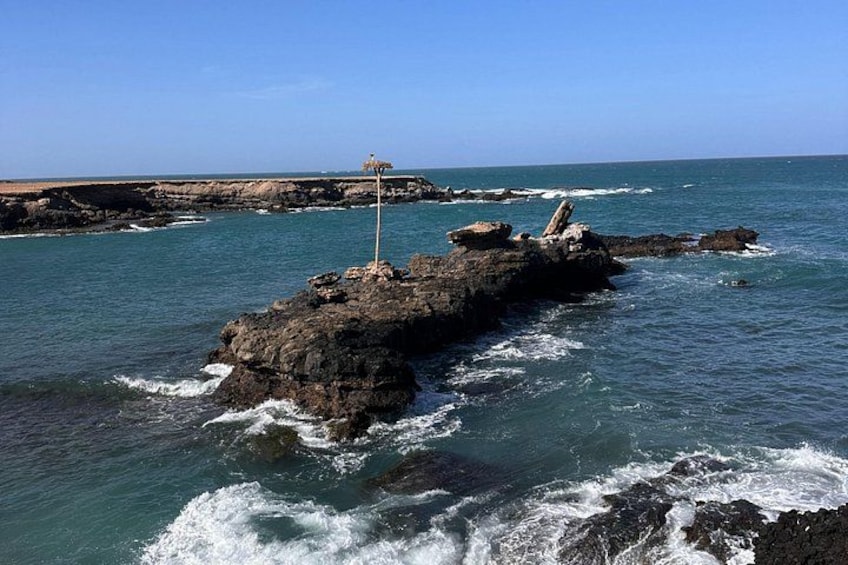 Una costa rocosa con olas rompiendo contra las rocas y un faro a lo lejos. 2