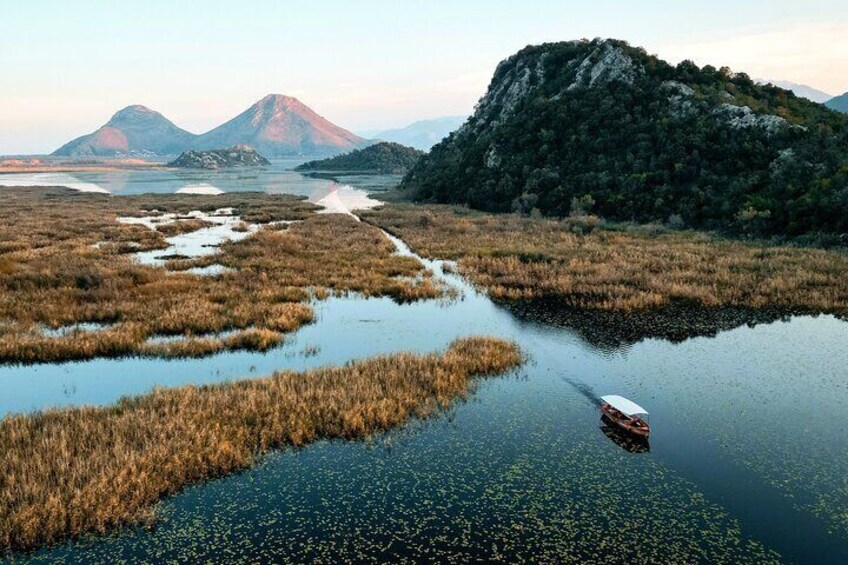 A boat on a calm river surrounded by marshland and mountains. 4
