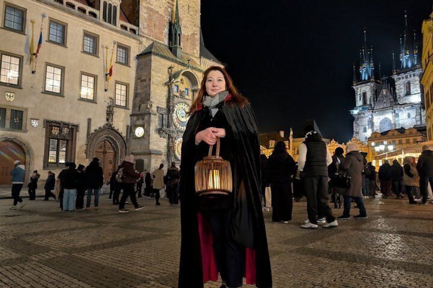 A person standing in a historic square with buildings and a clock tower in the background. 2