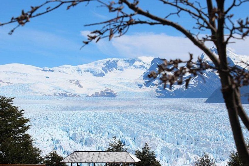 A glacier with a house in the foreground and mountains in the background. 3