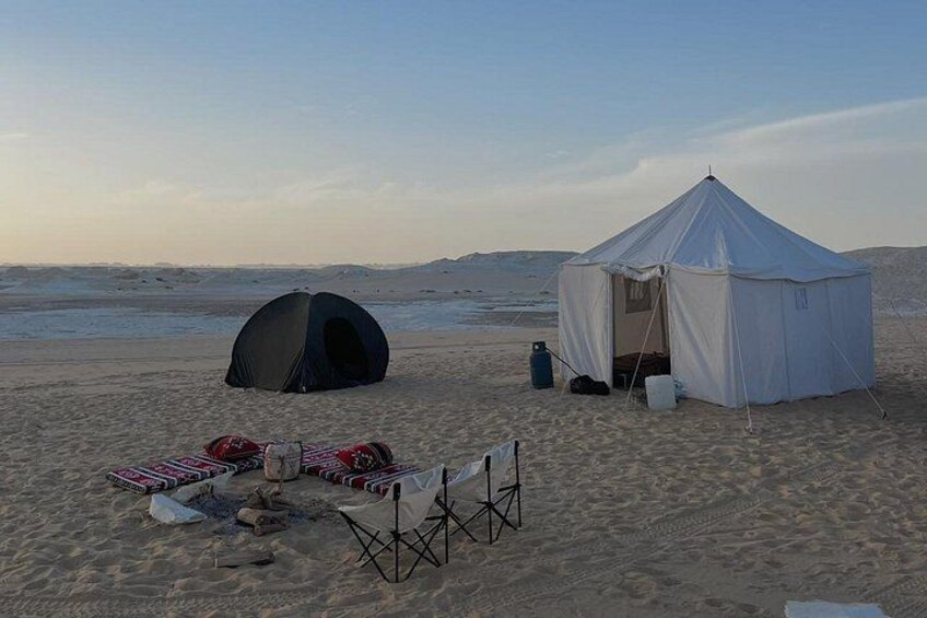 Ein Zelt am sandigen Strand, in der Nähe ein kleineres Zelt und Campingausrüstung. 4
