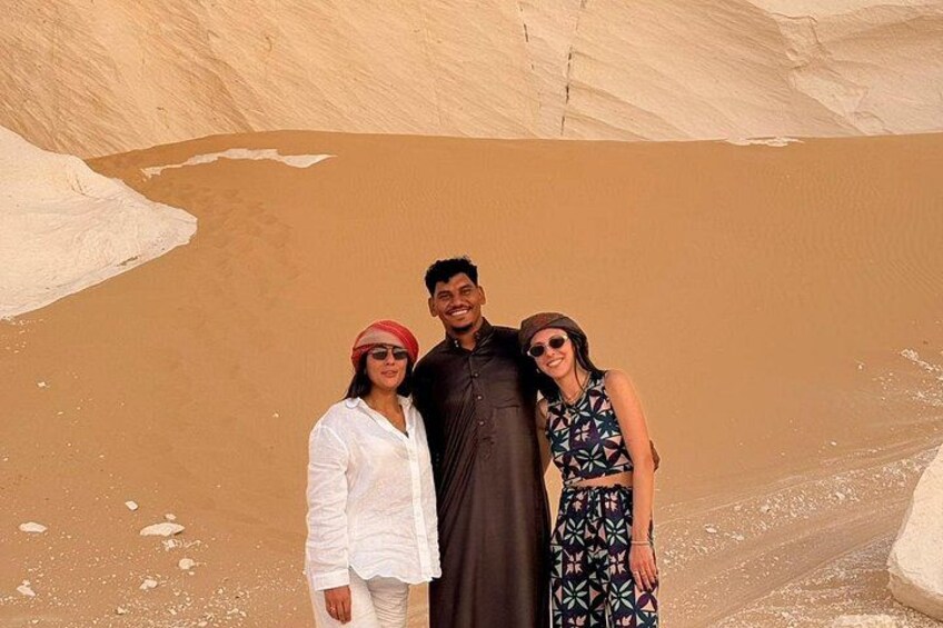 Eine Gruppe von Menschen steht in einer Wüstenlandschaft mit Sanddünen im Hintergrund. 2