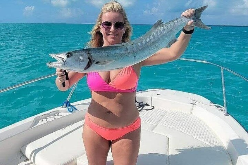 A person holding a fish on a boat with clear blue water in the background. 1