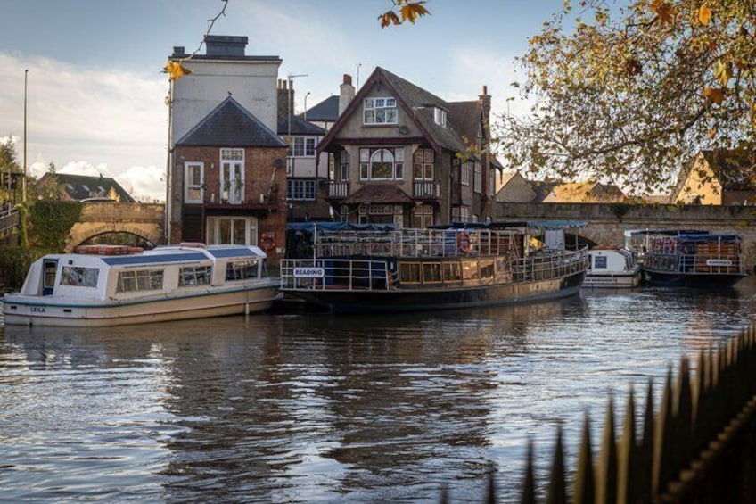 A river with boats docked at a pier, a historic building, and a bridge in the background. 3