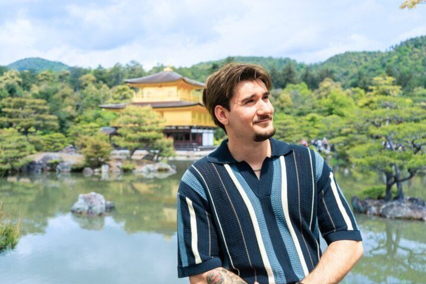 A person standing by a calm lake with a traditional building in the background. 2