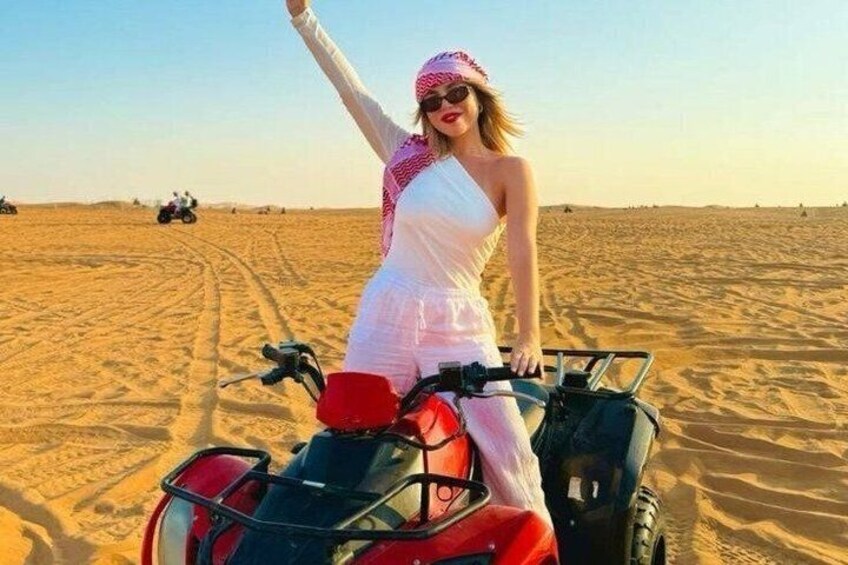 Una persona conduce un cuatrimoto en un desierto con dunas de arena y cielo despejado. 3