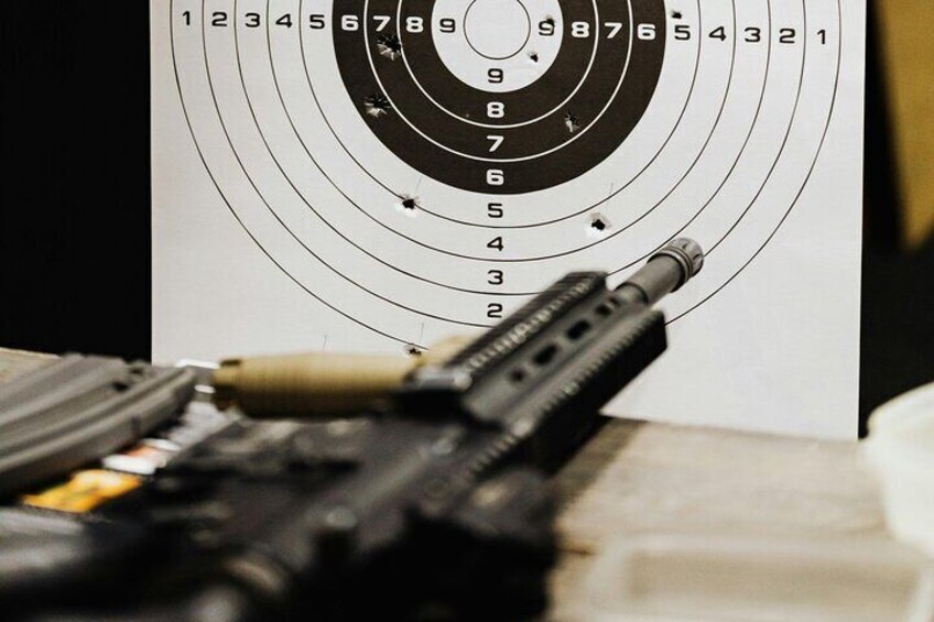 A handgun with a scope aimed at a target with concentric circles and numbers. 2