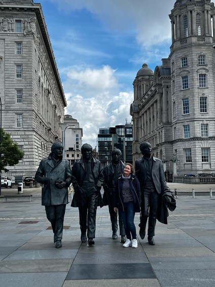 A statue of five figures walking in a line on a city square. 1