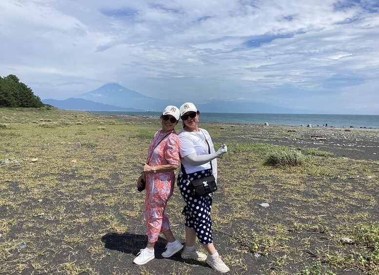 Two people standing on a beach with a mountain in the background. 3