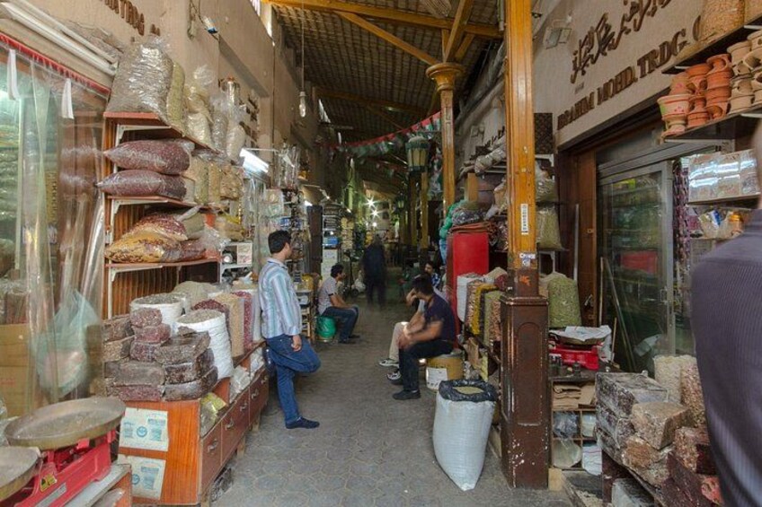 Une rue étroite bordée de boutiques où l’on peut admirer une variété de produits exposés sur des étagères et des tables. 4