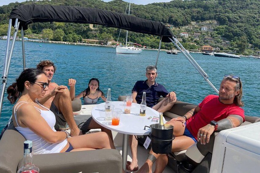 A group of people on a boat with a table in the center, surrounded by water and hills in the background. 4