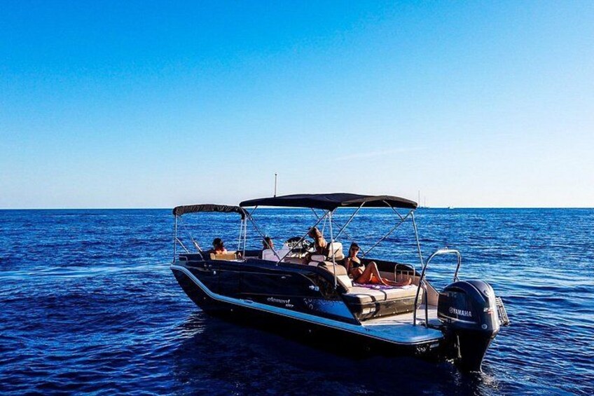 A boat with a canopy, people on board, and calm blue water. 2