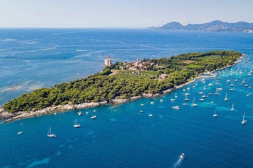 Vista aérea de una isla costera con aguas azul turquesa, numerosos veleros y una pequeña estructura tipo torre. 1