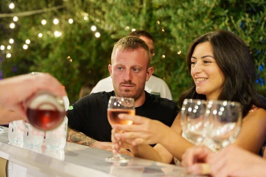 People toasting with wine glasses at an outdoor gathering. 4