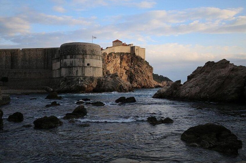 A coastal fortification with a flag, rocky shoreline, and waves. 5
