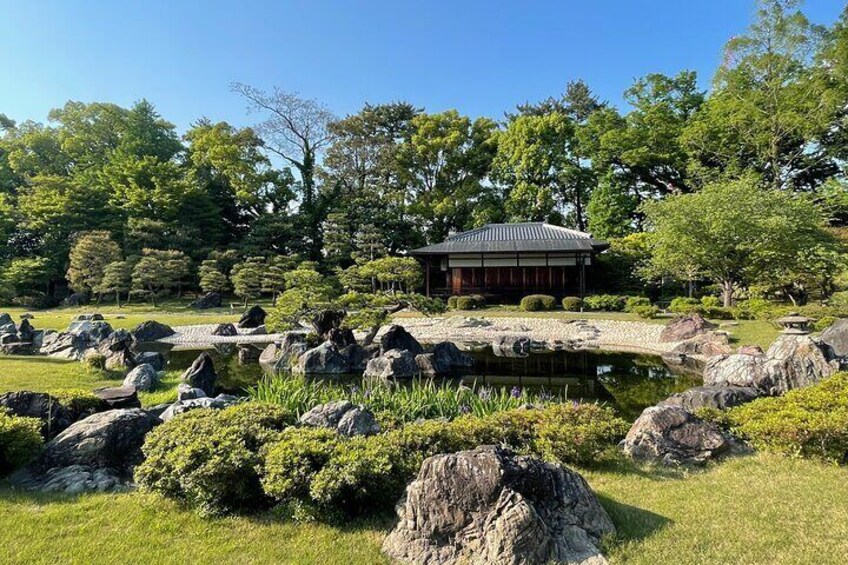 A traditional Japanese garden with a building, rocks, and trees. 4