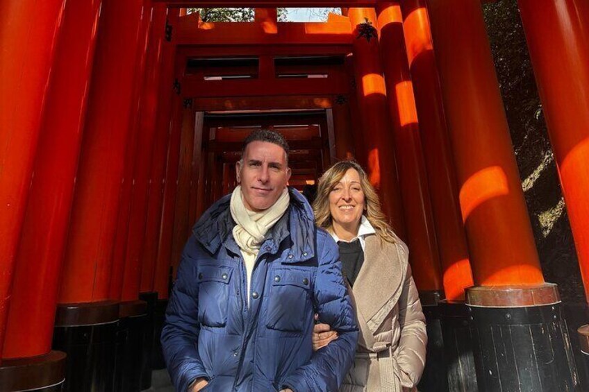 Two people standing in front of a red torii gate. 3