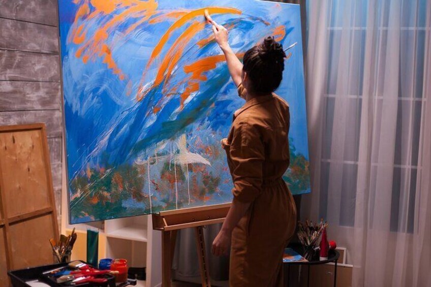 Una persona dipinge una grande tela con colori blu e arancio. 2