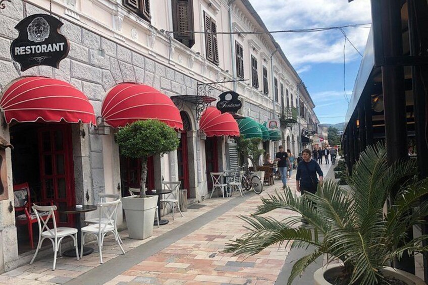 A street with outdoor seating, red umbrellas, and a sign that reads 'Restaurant.' 4
