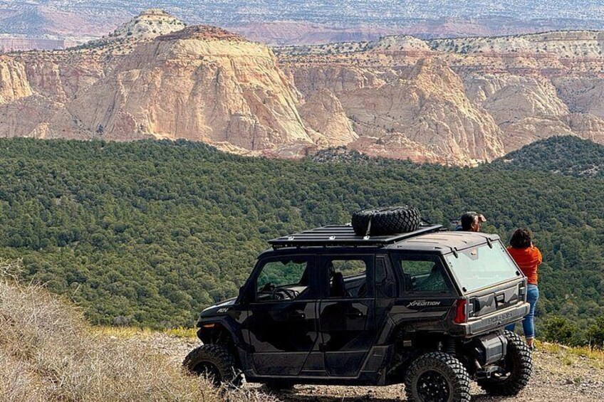 A black off-road vehicle parked on a grassy hill with a mountainous landscape in the background. 2