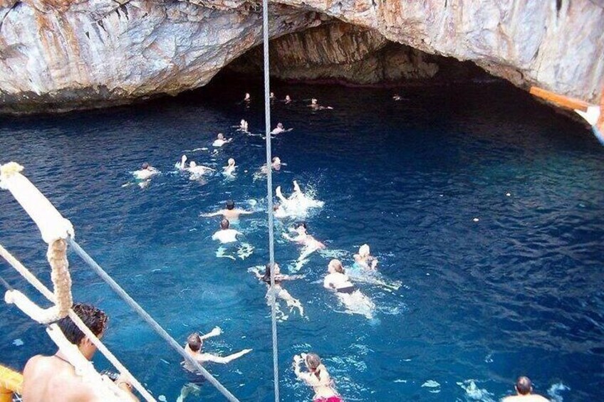 People swimming in a natural pool with a rocky cave entrance. 5
