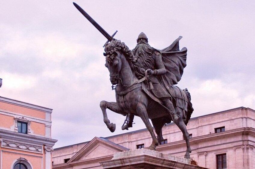 A statue of a figure on horseback, a building in the background, and a cloudy sky. 3