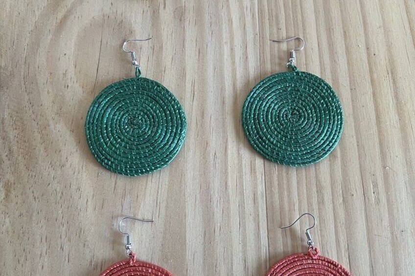 Un par de aretes circulares con diseño en espiral, uno verde y uno rojo, sobre una superficie de madera. 4