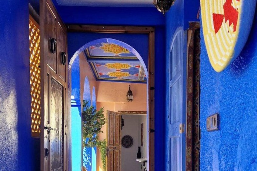 A hallway with blue walls, a wooden door, and a decorative ceiling. 4
