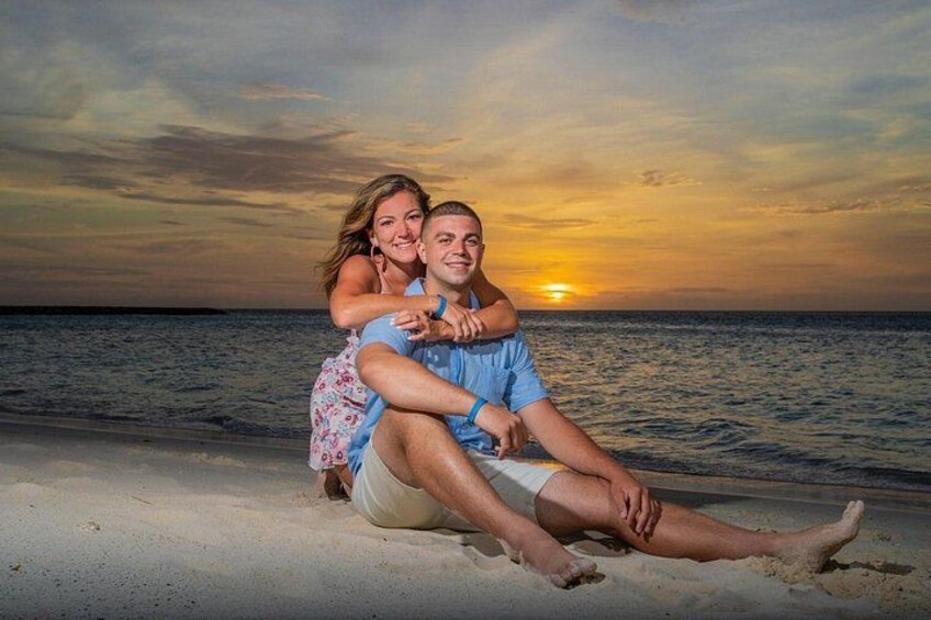 Una pareja sentada en la playa con el atardecer de fondo. 2