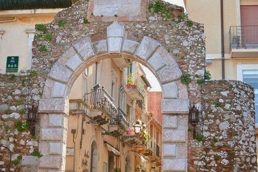 An ancient stone archway with a staircase leading into a building. 2