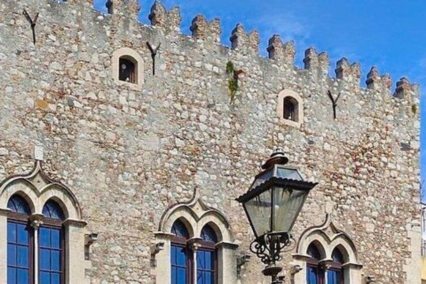 A stone castle with arched windows and a street lamp. 5