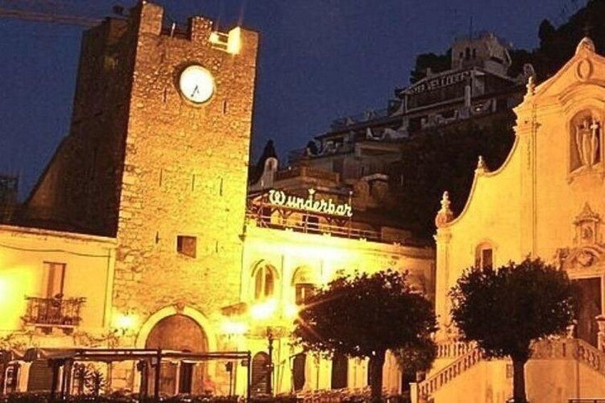 A historic building with a clock tower, a sign reading 'Wunderbar,' and a tree in the foreground. 4