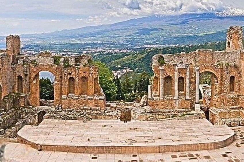 Ancient ruins with a stage and arches, overlooking a valley. 1