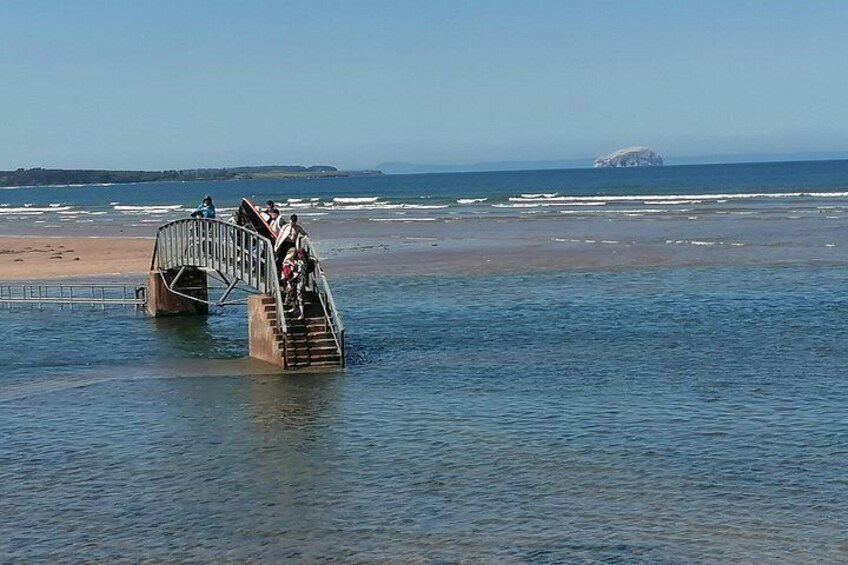 Een metalen brug over water, waar mensen overheen lopen. 4