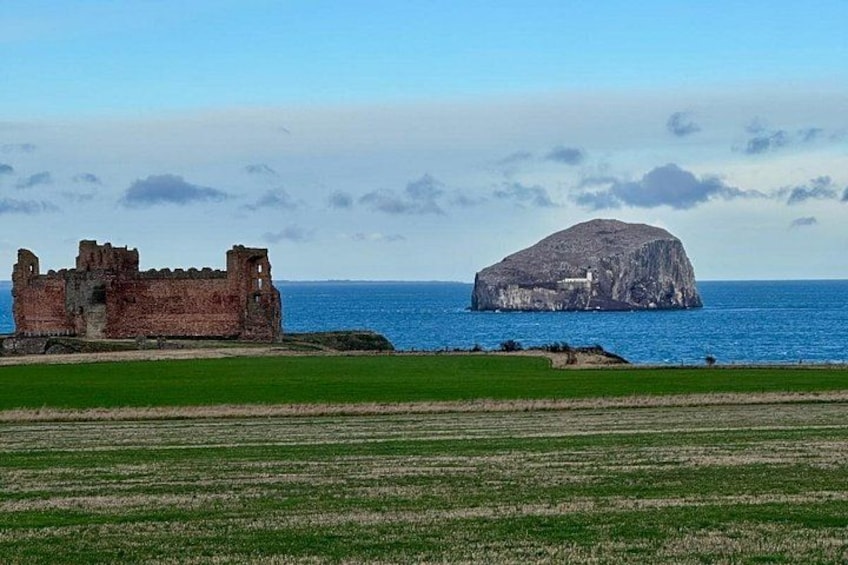 Un paisaje costero con un castillo en ruinas y una destacada formación rocosa. 1