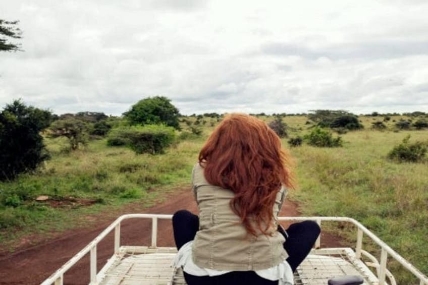 Une personne assise sur un banc en métal blanc, avec un paysage rural en arrière-plan. 2