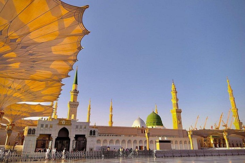 A mosque with multiple minarets and a green dome. 5