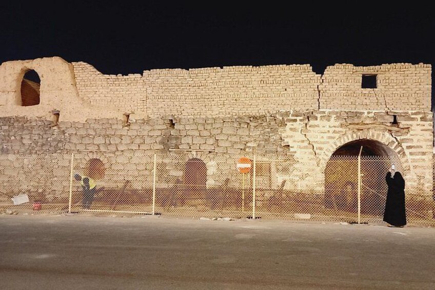 An ancient stone wall with arched openings and a person in traditional attire. 3