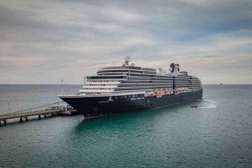 A large cruise ship docked at a pier with calm waters and a cloudy sky. 1