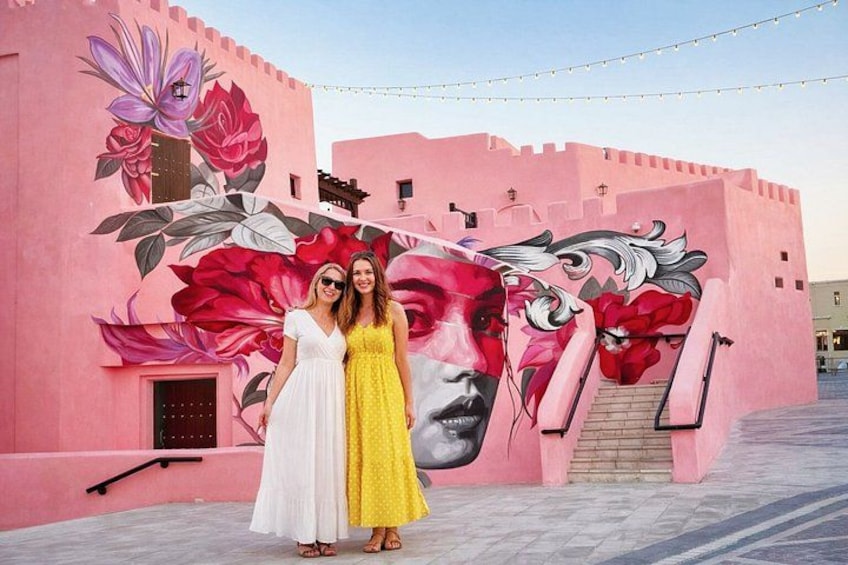 Un edificio rosa con un mural de flores y el rostro de una mujer. 2