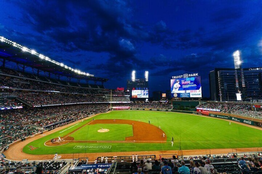 A baseball stadium at night with a large crowd, a baseball diamond, and advertisements on the outfield wall. 1