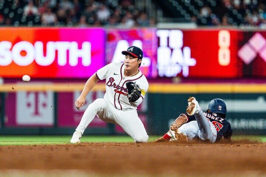 A baseball game in progress with a player sliding into a base and another player attempting to tag him out. 2