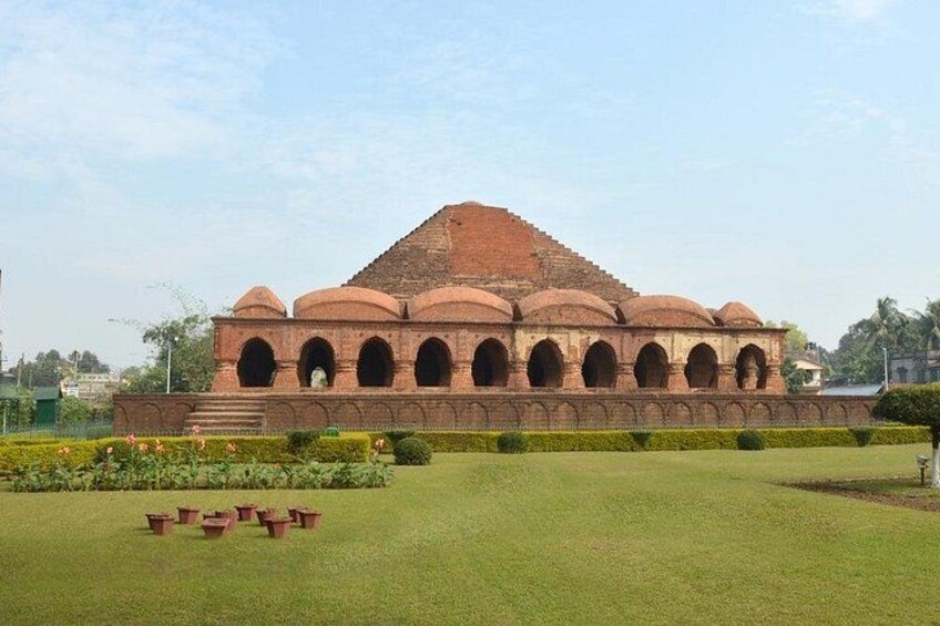 A large, historic building with multiple domes and arches, surrounded by a well-maintained lawn and flower beds. 4