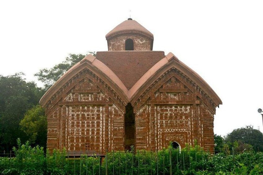 A brick building with a dome and arched entrance, surrounded by greenery. 3