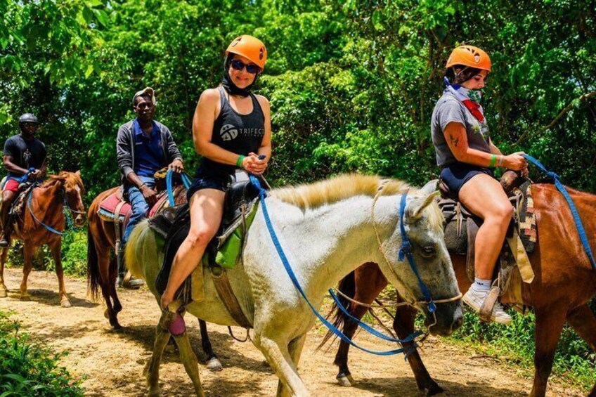 People riding horses on a dirt path surrounded by greenery. 2