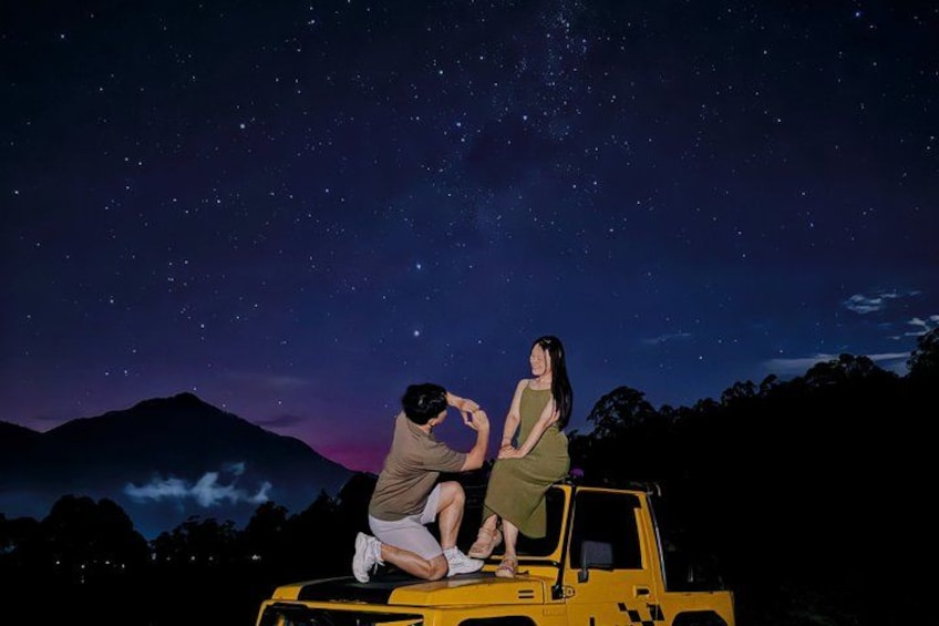 Dos personas sentadas en un vehículo amarillo bajo un cielo estrellado. 5
