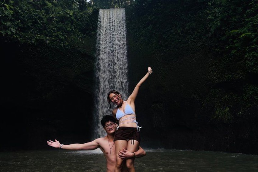 Una cascada con una persona cargando a otra sobre sus hombros en una zona boscosa. 4